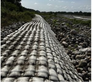Geotextil blanco con sacos arena protegiendo erosión ribereña