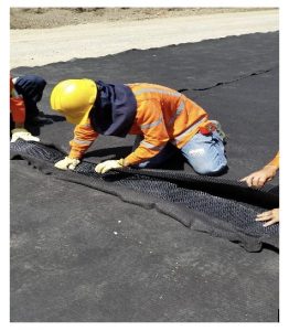 Obrero en chaleco naranja instalando asfalto en carretera