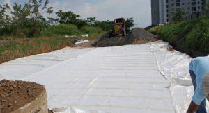Obra de construcción con geotextil blanco y maquinaria amarilla