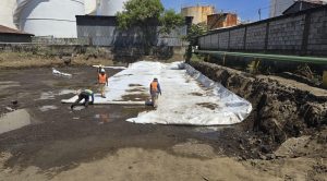 Trabajadores instalan geotextil en excavación junto a canal