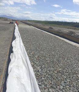 Trabajador instalando geotextil blanco en canal de grava