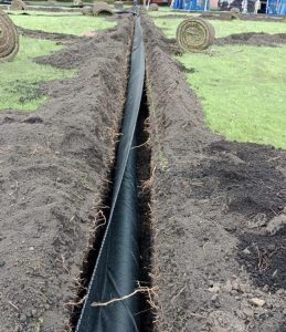 Tubería negra instalada en zanja excavada en terreno