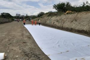 Obreros en obra con geomembrana blanca en excavación