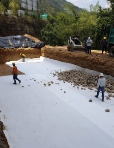 Trabajadores construyen cimentación con geotextil blanco en montaña
