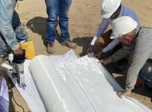 Trabajadores con cascos revisan tubería blanca en obra